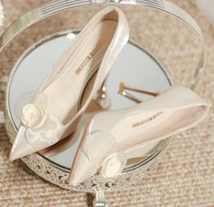 two pairs of wedding shoes sitting on top of a glass table next to a mirror