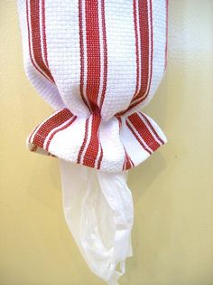 a red and white striped pillow hanging on the wall next to a toilet paper roll