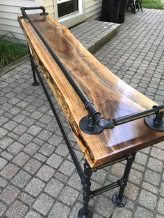 a wooden bench sitting on top of a metal stand next to a brick walkway and house