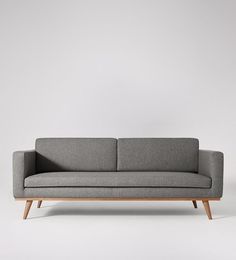 a gray couch sitting on top of a white floor next to a wooden frame chair