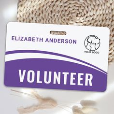 a volunteer badge sitting on top of a white table next to some dried flowers and a straw hat