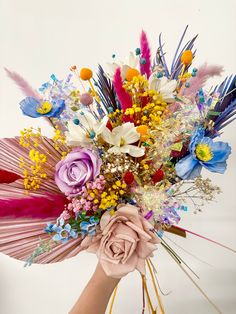 a person holding a bouquet with flowers and feathers