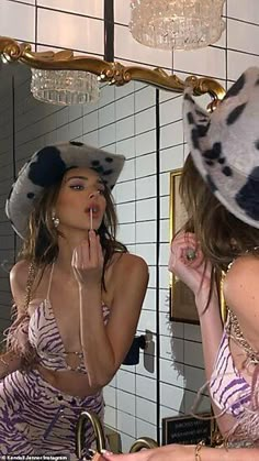 a woman is brushing her teeth in front of a mirror while wearing a cow print bathing suit