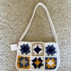 a crocheted purse with blue, yellow and white stars on it sitting on the floor