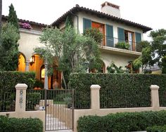 a large house with hedges on the front and gated in area to it's side