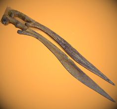 two old scissors are laying side by side on a yellow background, one is broken and the other has rusted