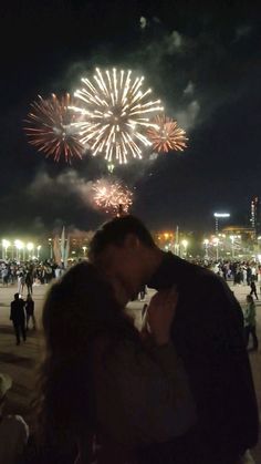 a man and woman kissing in front of fireworks