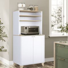 a white cabinet with a microwave on top of it next to a plant and window