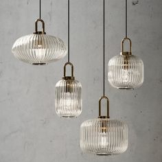 three clear glass pendants hanging from a ceiling fixture in a room with concrete walls