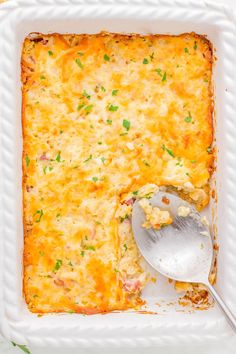 a casserole dish with a spoon in it on a white plate next to a fork