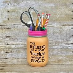 a jar filled with pens and scissors on top of a wooden table