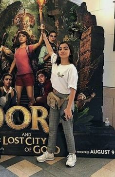 a woman standing in front of a poster for dora and the lost city of gold