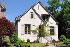 a white brick house surrounded by trees and bushes