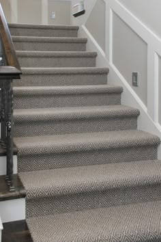 a staircase with carpeted steps leading up to the first floor and another handrail