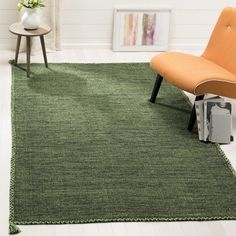 a green rug in a living room with an orange chair and side table on the floor