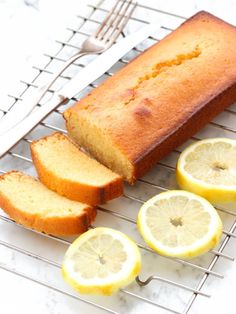 a loaf of lemon pound cake on a cooling rack next to sliced lemons and a knife