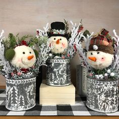 three snowmen are sitting in tin cans on a table