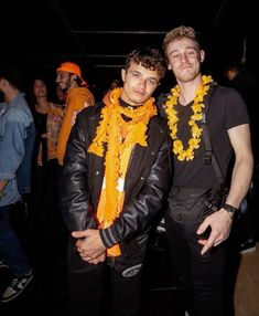 two men standing next to each other wearing leis