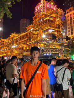 a man standing in front of a building with lights on it's sides at night