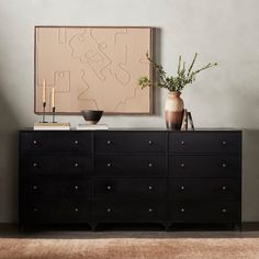 a black dresser with two vases and a painting on the wall