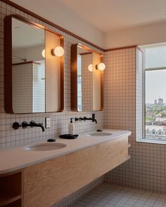 a bathroom with two sinks and three mirrors on the wall next to each other in front of a window