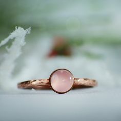 This Copper Rose Quartz Ring features a 6 mm cabochon that has been securely set in a highly polished fine copper bezel. The band is made of a sturdy round Copper wire that has been given a hammer texture, then carefully finished for comfortable wear. Our setting process involves carefully tightening the bezel around the stone, creating a water-tight seal with no stone movement. These beautiful rings make unique promise rings, lovely stacking rings, great birthstone rings, or just a wonderful lo Rose Gold Stackable Rings With Bezel Setting For Gift, Hand Forged Round Moonstone Ring, Stackable Rose Gold Moonstone Ring, Stackable Round Moonstone Ring In Rose Gold, Rose Gold Gemstone Stackable Rings, Hand Forged Rose Gold Round Jewelry, Hand Forged Round Rose Gold Jewelry, Hand Forged Rose Gold Jewelry, Rose Gold Moonstone Ring With Birthstone