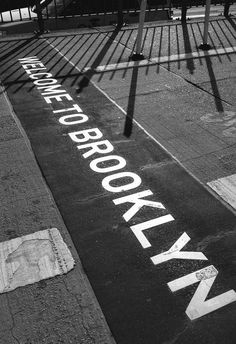 a black and white photo of a street with the word brooklyn painted on it's side