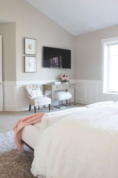 a bedroom with a bed, chair and television on the wall