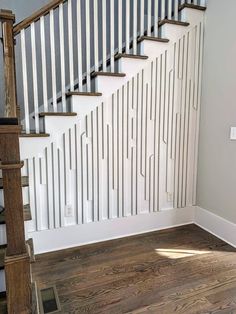 an empty room with stairs and hard wood flooring on the side of the wall