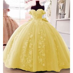 a yellow ball gown is on display in a room with mannequins and flowers