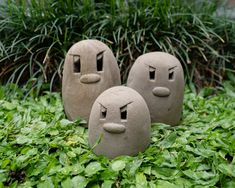 three cement faces are sitting in the grass