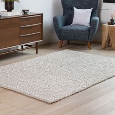 a living room with a blue chair and white rug