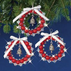 two red and white christmas ornaments hanging from a pine tree with bells on it's sides