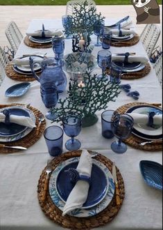 the table is set with blue dishes and place settings