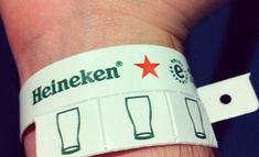 a person wearing a wristband that has beer mugs on it and the words heineken written on it