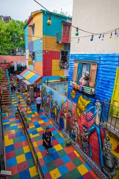 an overhead view of a colorful street with people walking down the sidewalk and paintings on the walls