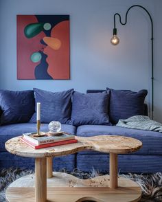 a living room with a blue couch and coffee table in front of a painting on the wall