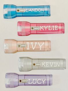 four personalized lighters are lined up on a white surface with the names of different colors