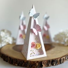 three small white pyramids with pink and yellow flowers on them sitting on a piece of wood