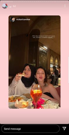 two women sitting at a table with food in front of them