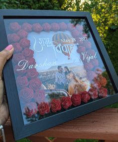 a person holding up a framed photo with roses on it