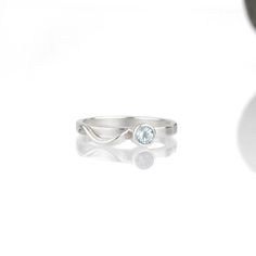 A wave of sterling silver rises up out of the base of a sparkling gemstone, and tumbles in a tiny rivulet down the side of the band. The Cascade ring is dainty and elegant when worn alone; but this slender stacking ring is designed to nestle closely with one or more accompanying bands. This sparkly sky blue topaz and sterling silver ring is handcrafted and made to order. Wear it by itself, or customize a stack of skinny bands and coordinating gemstone rings - the possibilities to mix and match a Promise White Gold Topaz Ring In Sterling Silver, White Gold Sterling Silver Topaz Promise Ring, Promise Topaz Ring In White Gold Sterling Silver, Minimalist Topaz Jewelry For Weddings, Minimalist Blue Topaz Solitaire Jewelry, Sterling Silver Diamond Ring With Single Diamond, Adjustable Sterling Silver Ring With Single Diamond, Silver Jewelry With Tension Setting White Topaz, Sterling Silver Jewelry With Tension Setting In Round Band