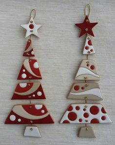 two red and white christmas trees are hanging from gold earwires on a table