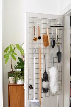 a rack with brooms, brushes and other cleaning products hanging on it's wall