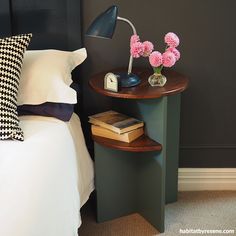 a nightstand with flowers on it next to a bed