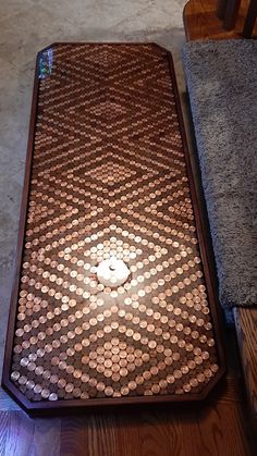 a wooden table topped with lots of coins on top of a hard wood floor next to a rug