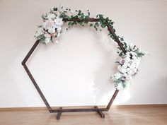 a wooden frame with flowers and greenery on the top is against a white wall