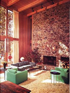 a living room filled with furniture and a fire place in front of a stone wall