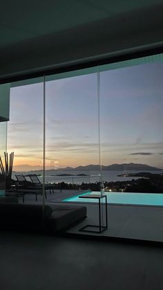 a living room filled with furniture next to a large window overlooking the ocean at night