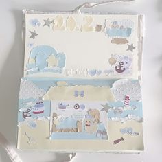 an open baby's scrapbook with paper cut outs and ribbon around the edges